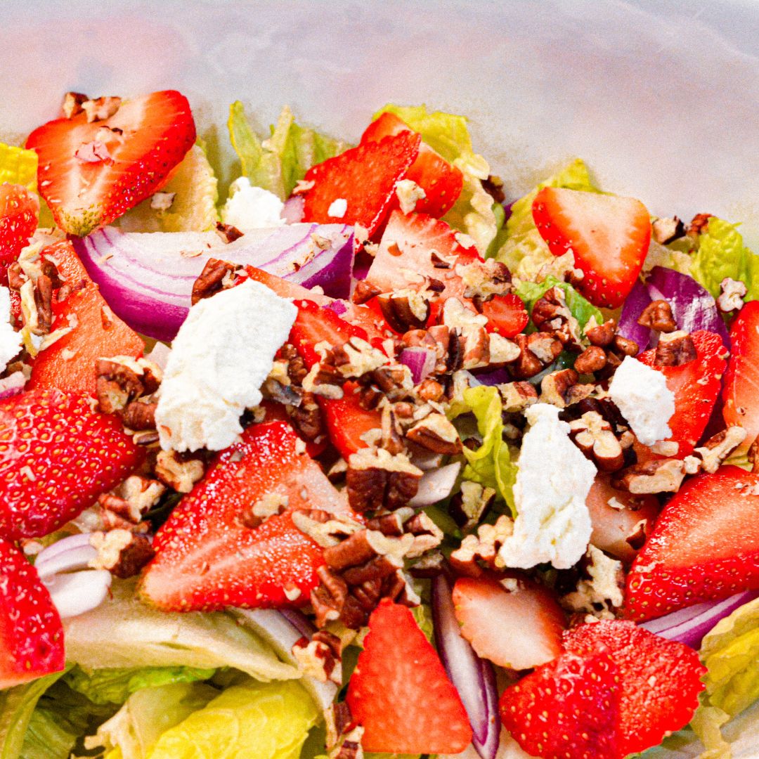 In a large bowl, combine chopped romaine, cucumber, strawberries, cheese, and green onions.