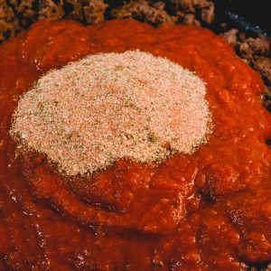 To the browned meat add one jar of spaghetti sauce, add the zesty spaghetti seasoning packet. Stir to combine.