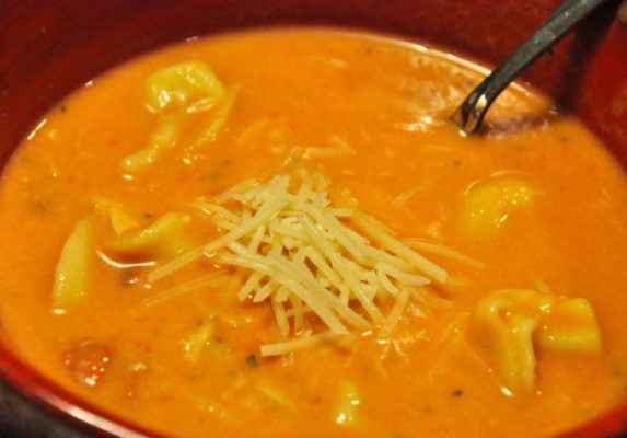 A rich and creamy soup combining chicken, tortellini, and a tomato-based broth, offering warmth and flavor in every spoonful.