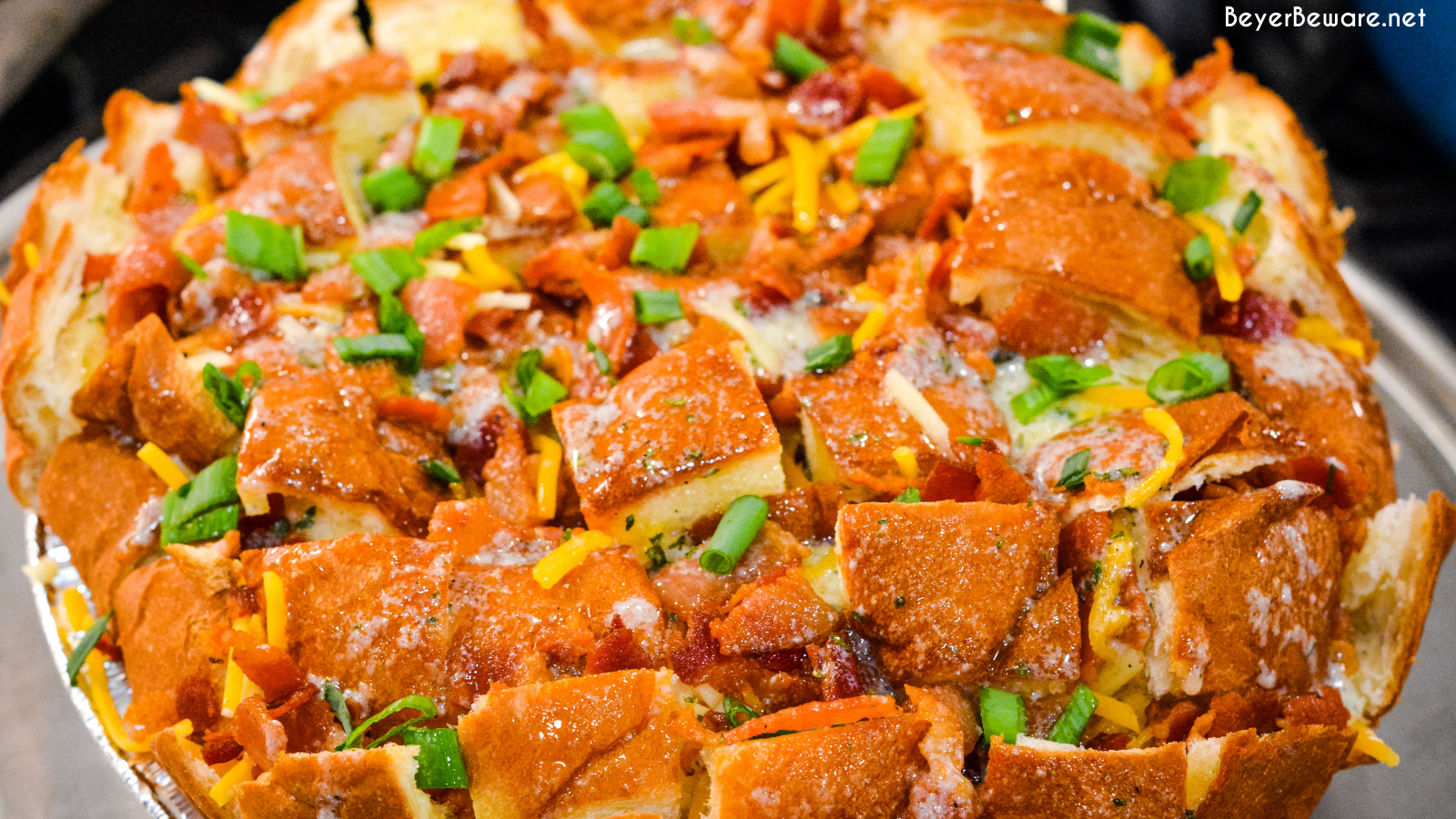 The cheesy ranch bacon pull-apart bread recipe is an easy appetizer made with a Hawaiian Bread round loaf that is filled with bacon, cheese, and, green onions ranch butter then baked to gooey crack bread perfection.