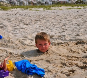 Boy buried in sand up to his neck
