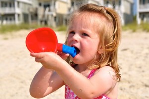 little girl chewing on sand toy