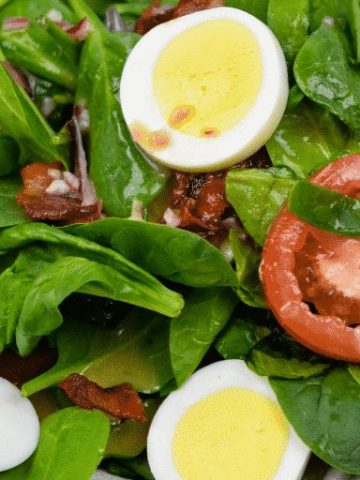 Spinach salad with hot bacon dressing is an easy spinach salad recipe made with bacon, tomatoes, and eggs tossed in a warm dressing that has a mixture of tangy sweetness and salty from the bacon. #bacon #spinach #salad #bacon #BaconDressing #SpinachSalad #EasterRecipes #keto