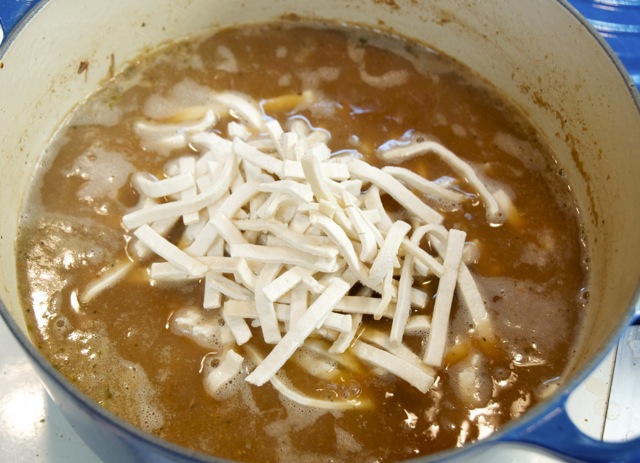 Frozen egg noodles being added to beef and broth