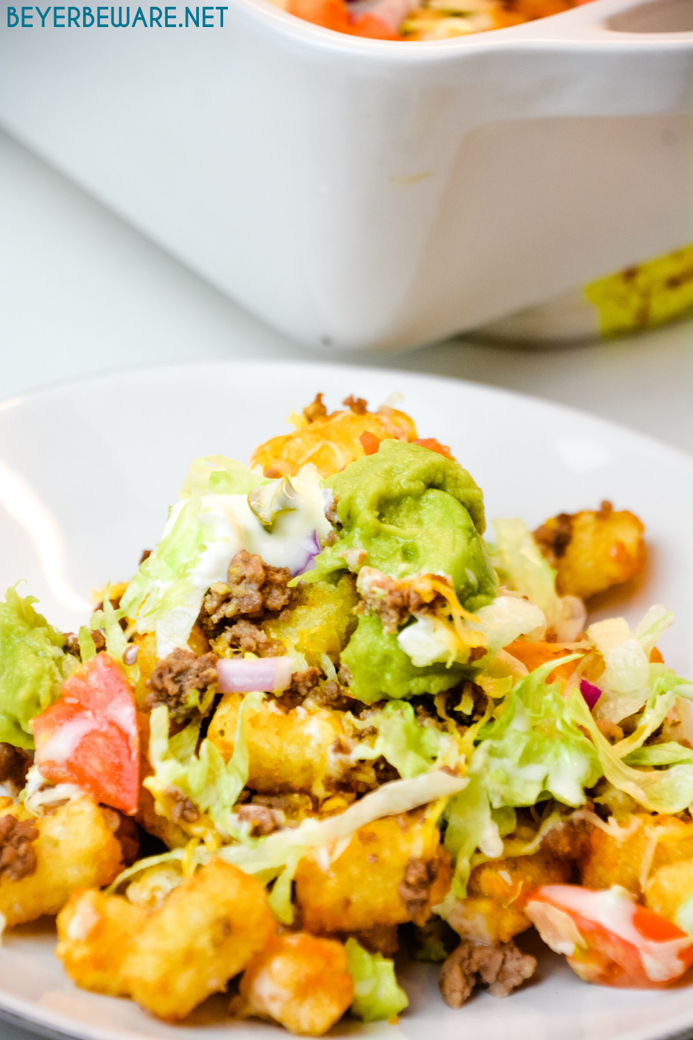 Totchos are the tater tot version of nachos with all your favorite taco toppings like ground beef, lettuce, tomatoes, and cheese.