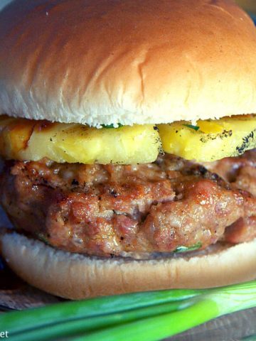 This grilled pineapple pork burger recipe mixes Asian seasonings with ground pork then topped with a slice of grilled pineapple and a teriyaki sauce.