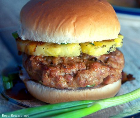 This grilled pineapple pork burger recipe mixes Asian seasonings with ground pork then topped with a slice of grilled pineapple and a teriyaki sauce.