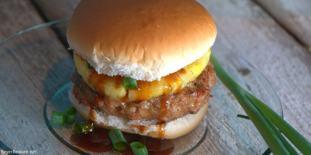 This grilled pineapple pork burger recipe mixes Asian seasonings with ground pork then topped with a slice of grilled pineapple and a teriyaki sauce.