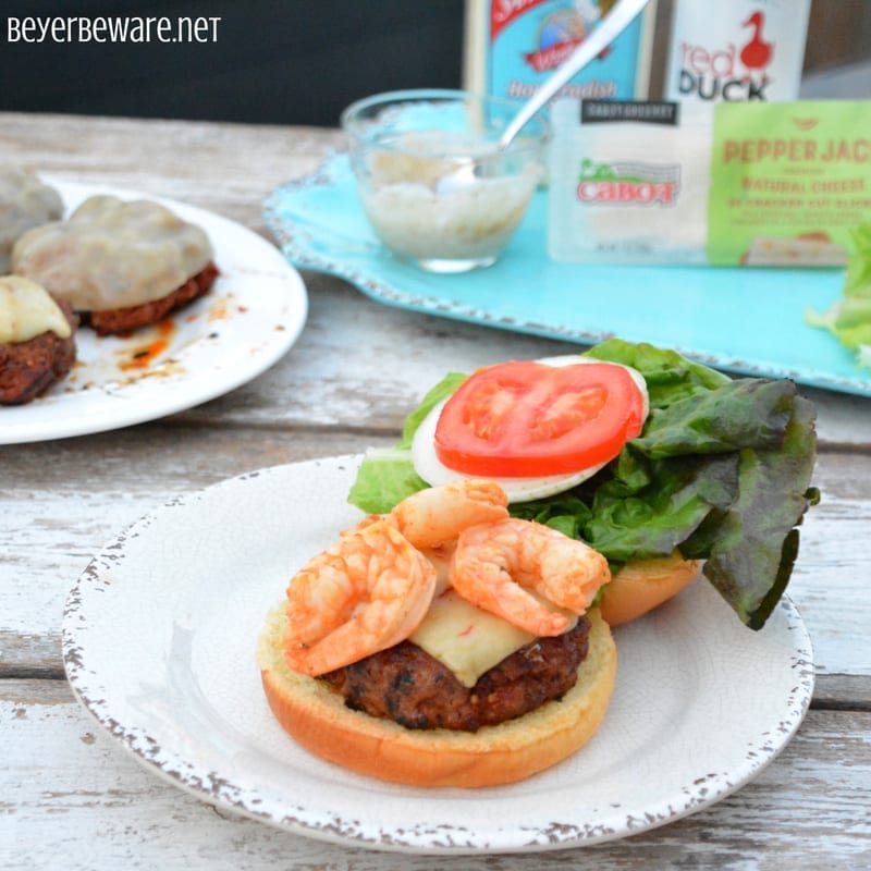 The Cajun pork burgers topped with shrimp and then drenched in a Cajun aioli combine ground pork, chorizo, with a Cajun seasoned horseradish mayonnaise for a perfect surf and turf burger recipe.