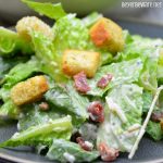 Easy bacon caesar salad is a simple combination of the basic Caesar salad ingredients of romaine lettuce, parmesan cheese, caesar dressing and croutons and taken up a notch with the addition of bacon.