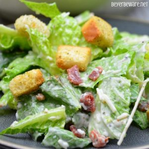 Easy bacon caesar salad is a simple combination of the basic Caesar salad ingredients of romaine lettuce, parmesan cheese, caesar dressing and croutons and taken up a notch with the addition of bacon.