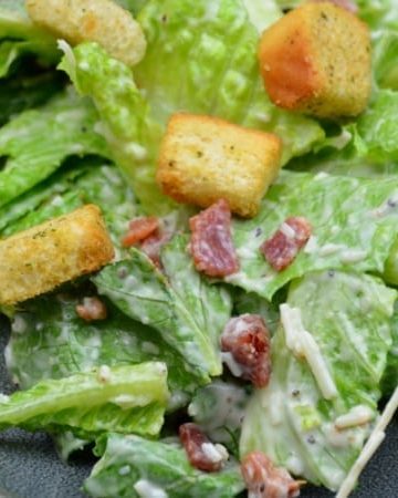 Easy bacon caesar salad is a simple combination of the basic Caesar salad ingredients of romaine lettuce, parmesan cheese, caesar dressing and croutons and taken up a notch with the addition of bacon.