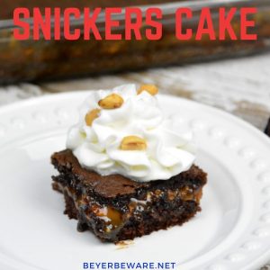 Snickers cake recipe takes a chocolate cake mix up a notch by filling it with caramel, peanuts and chocolate chips making for the cake version of a favorite candy bar. #CakeMix #Snickers #Caramel #Chocolate