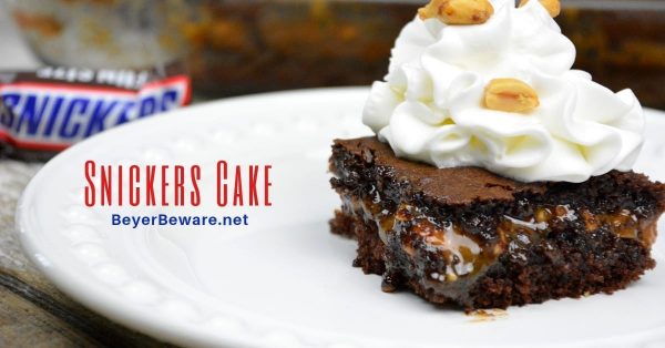 Snickers cake recipe takes a chocolate cake mix up a notch by filling it with caramel, peanuts and chocolate chips making for the cake version of a favorite candy bar. #CakeMix #Snickers #Caramel #Chocolate