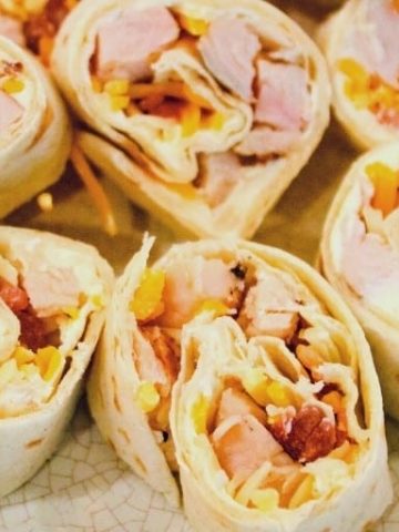 Chicken bacon ranch roll-ups are a quick tortilla wrap sandwich recipe sliced into pinwheels and filled with ranch cream cheese, chicken, bacon, and cheese.
