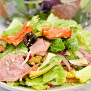 Italian antipasto salad is a hearty dinner salad with a romaine lettuce base and filled up with salami, pepperoni, tomatoes, cucumbers, onions, olives, banana peppers, and cheese dressed with a homemade Italian dressing.