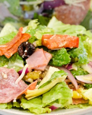 Italian antipasto salad is a hearty dinner salad with a romaine lettuce base and filled up with salami, pepperoni, tomatoes, cucumbers, onions, olives, banana peppers, and cheese dressed with a homemade Italian dressing.