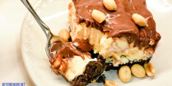 Peanut buster parfait ice cream dessert is a 13X9 ice cream cake with layers of crushed Oreos, vanilla ice cream, peanuts, and homemade chocolate sauce. 