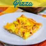 Cheesy bacon breakfast pizza is made with a refrigerated pizza crust, cheese sauce, scrambled egg, and bacon, topped off with more cheese and garlic butter for a decadent breakfast treat.