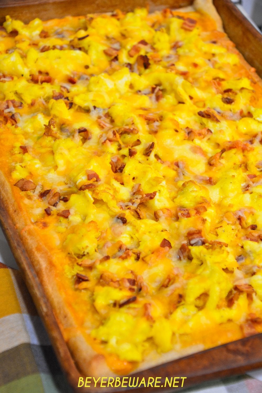 Cheesy bacon breakfast pizza is made with a refrigerated pizza crust, cheese sauce, scrambled egg, and bacon topped off with more cheese and garlic butter for a decadent breakfast treat.