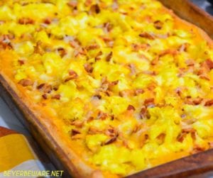 Cheesy bacon breakfast pizza is made with a refrigerated pizza crust, cheese sauce, scrambled egg, and bacon topped off with more cheese and garlic butter for a decadent breakfast treat.