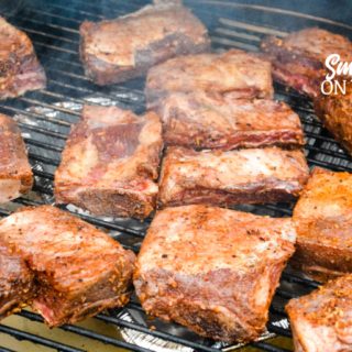 Grilled beef short ribs on the Big Green Egg are smoked with a beef barbecue rub and then slow-cooked to their final temperature in a bath of red wine, butter, and beef broth. 