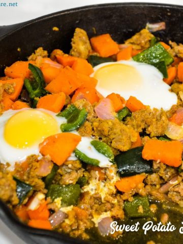 Sweet potato hash with sausage and eggs is a hearty breakfast skillet made with diced sweet potatoes, spicy sausage, onions, and poblano peppers with fried or poached eggs over the top.