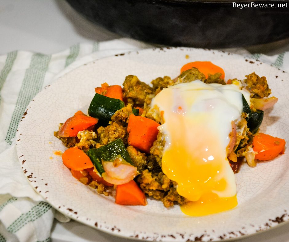 Sweet potato hash with sausage and eggs is a hearty breakfast skillet made with diced sweet potatoes, spicy sausage, onions, and poblano peppers with fried or poached eggs over the top.