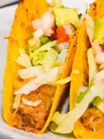 Creamy ground beef baked tacos are made with corn or flour shells, ground beef, taco seasoning, cream cheese, and salsa before topping with shredded cheese.