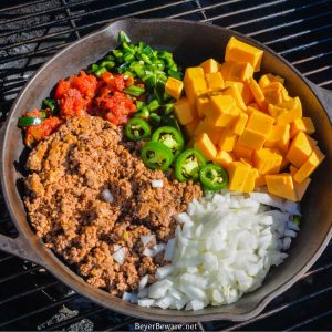 Smoked queso is your favorite queso dip made with Velveeta, Rotel, onions, taco meat, and peppers made in a cast-iron skillet on your smoker or grill.
