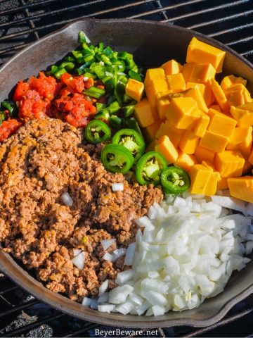 Smoked queso is your favorite queso dip made with Velveeta, Rotel, onions, taco meat, and peppers made in a cast-iron skillet on your smoker or grill.