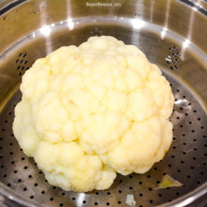 Cheesy Frosted Cauliflower is a whole head of cauliflower, steamed and then frosted with a combination of mayonnaise and mustard and then covered in cheese before quickly roasting in the oven.