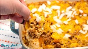 Sloppy Joe Dip has a cream cheese base and topped with an easy sloppy joe ground beef mixture and topped off with shredded cheese and onions, baked to a gooey, meaty goodness and then scooped up with corn chips.