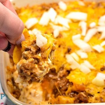 Sloppy Joe Dip has a cream cheese base and topped with an easy sloppy joe ground beef mixture and topped off with shredded cheese and onions, baked to a gooey, meaty goodness and then scooped up with corn chips.