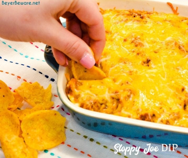 Sloppy Joe Dip has a cream cheese base and topped with an easy sloppy joe ground beef mixture and topped off with shredded cheese and onions, baked to a gooey, meaty goodness and then scooped up with corn chips.