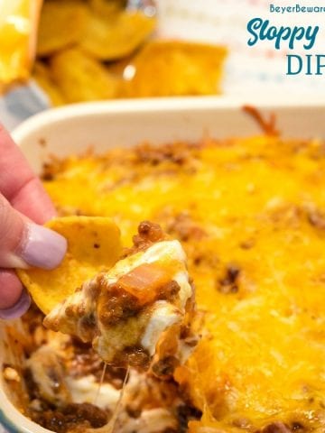 Sloppy Joe Dip has a cream cheese base and topped with an easy sloppy joe ground beef mixture and topped off with shredded cheese and onions, baked to a gooey, meaty goodness and then scooped up with corn chips.