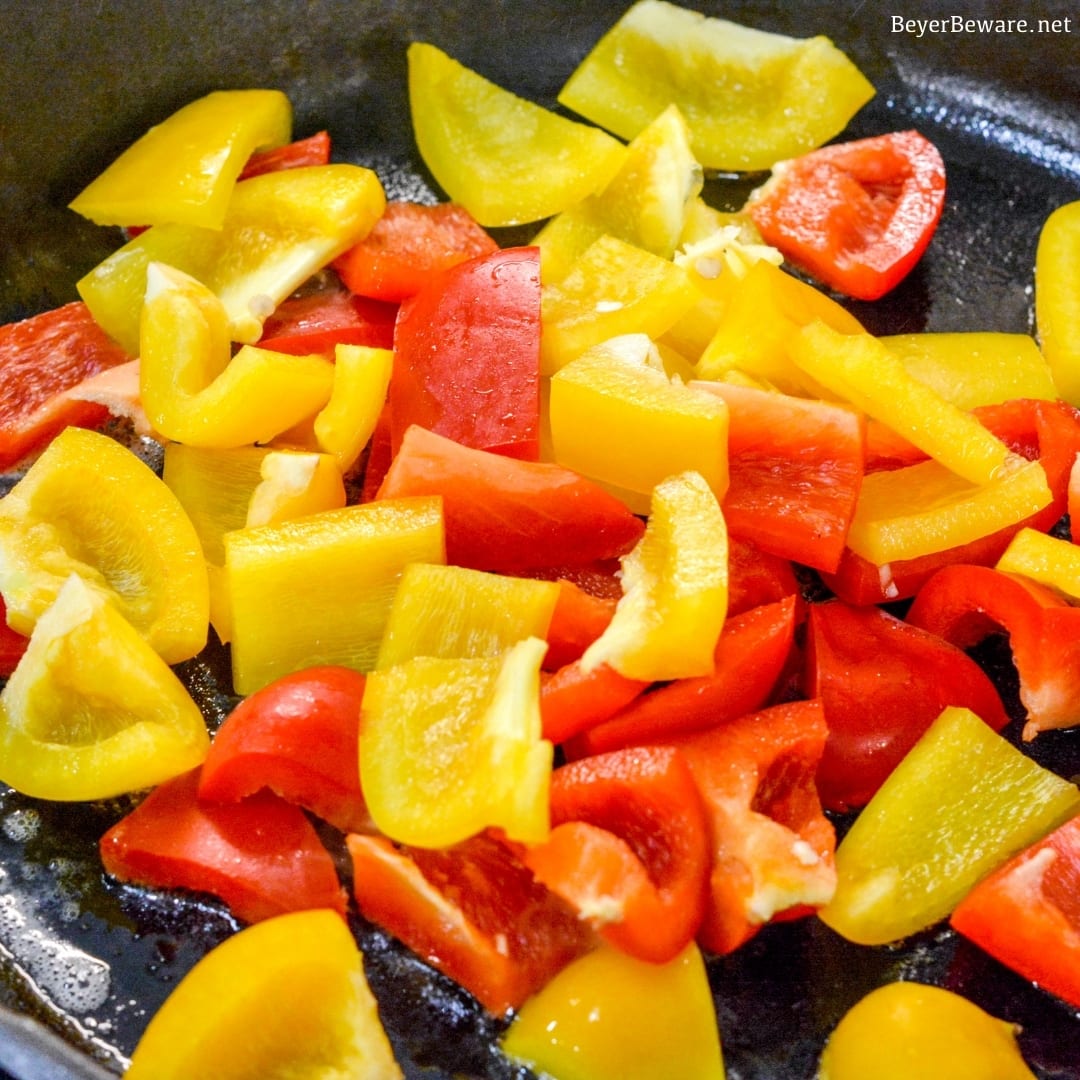 bell peppers sautéing in a cast iron skillet