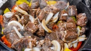 Garlic pepper steak bites recipe is an easy cast iron steak skillet meal made with an easy marinated sirloin steak recipe, garlic, onions, and bell peppers served over mashed potatoes or rice.