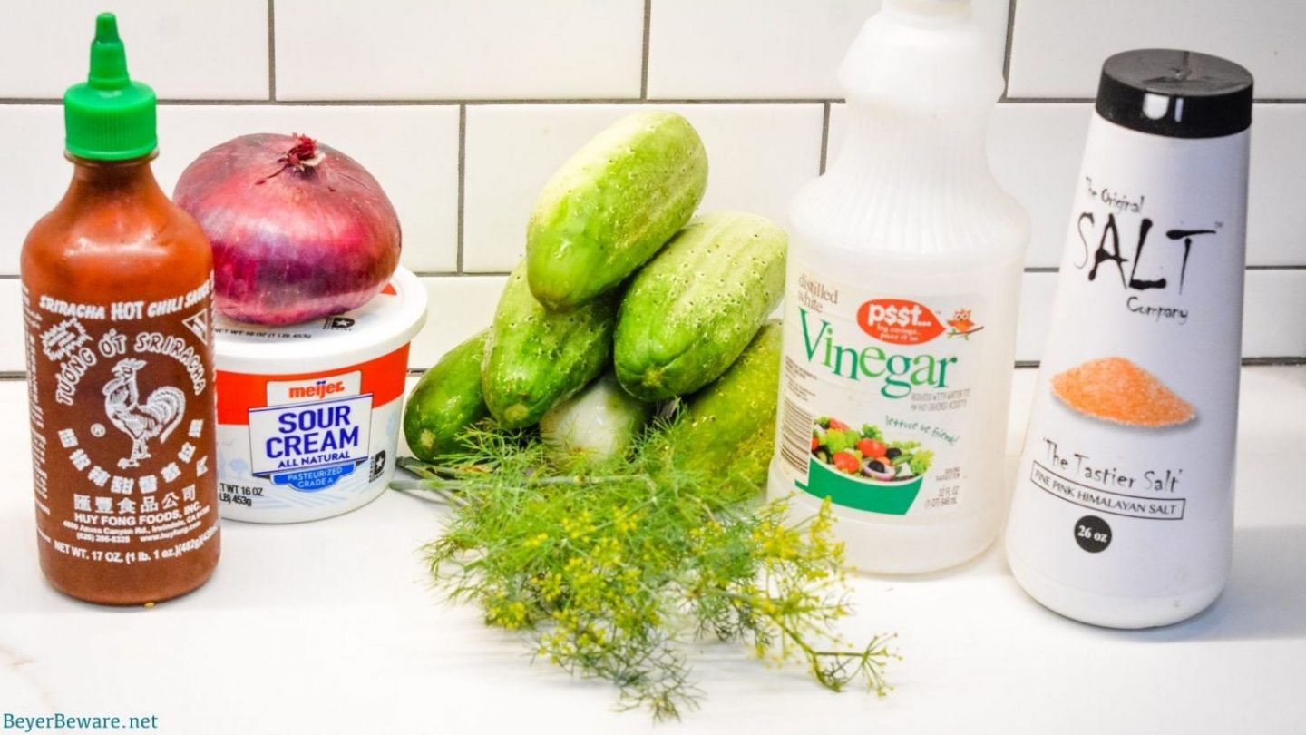 Cucumber and sour cream salad ingredients - cucumbers, onions, sour cream, hot sauce, dill weed, and vinegar.