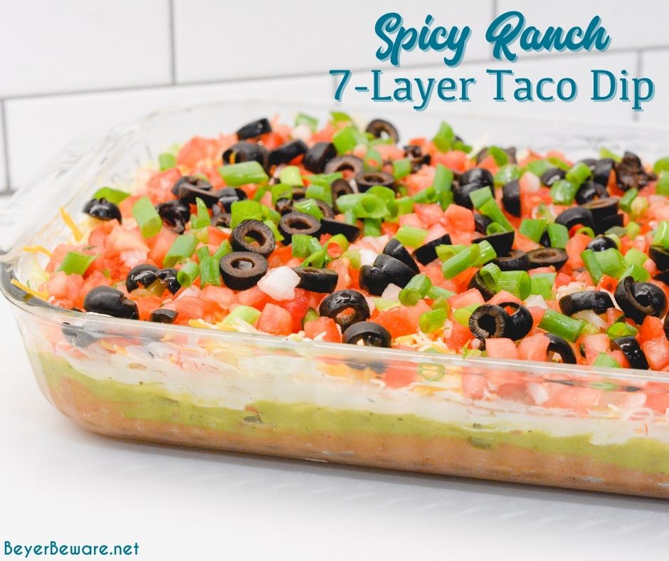 Spicy ranch 7-layer taco dip is Layers of taco-seasoned refried beans, guacamole, sour cream with ranch, lettuce, cheese, pico de gallo, olive, and cheese.