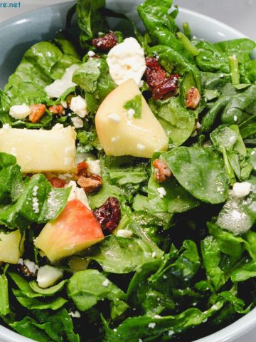 Apple spinach salad is a sweet and savory mixture of spinach, apples, pecans, cranberries, and feta cheese finished with a maple dijon vinaigrette.