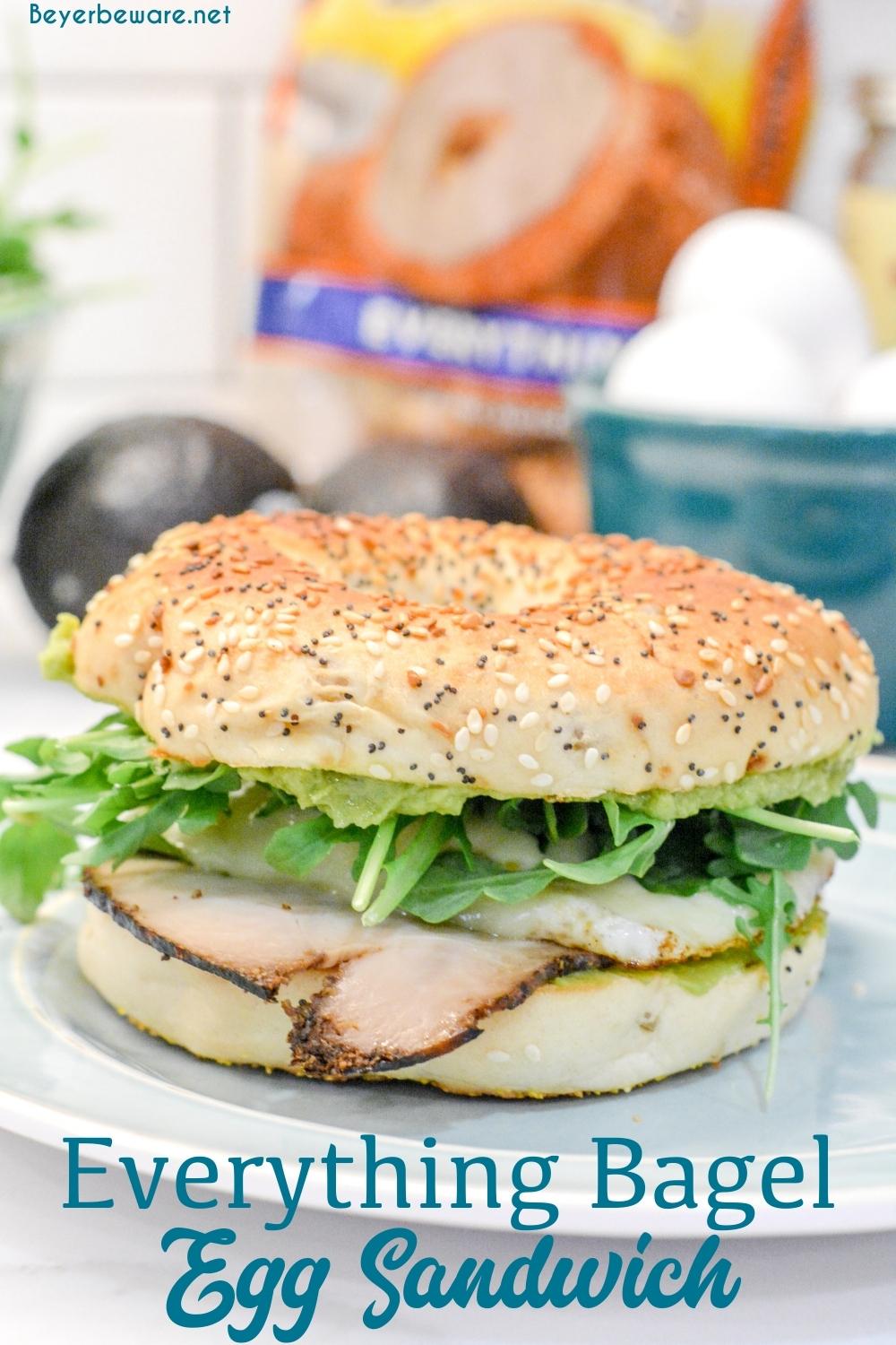 This everything bagel egg sandwich is filled with avocado, turkey, egg, cheese, and topped off with arugula. 