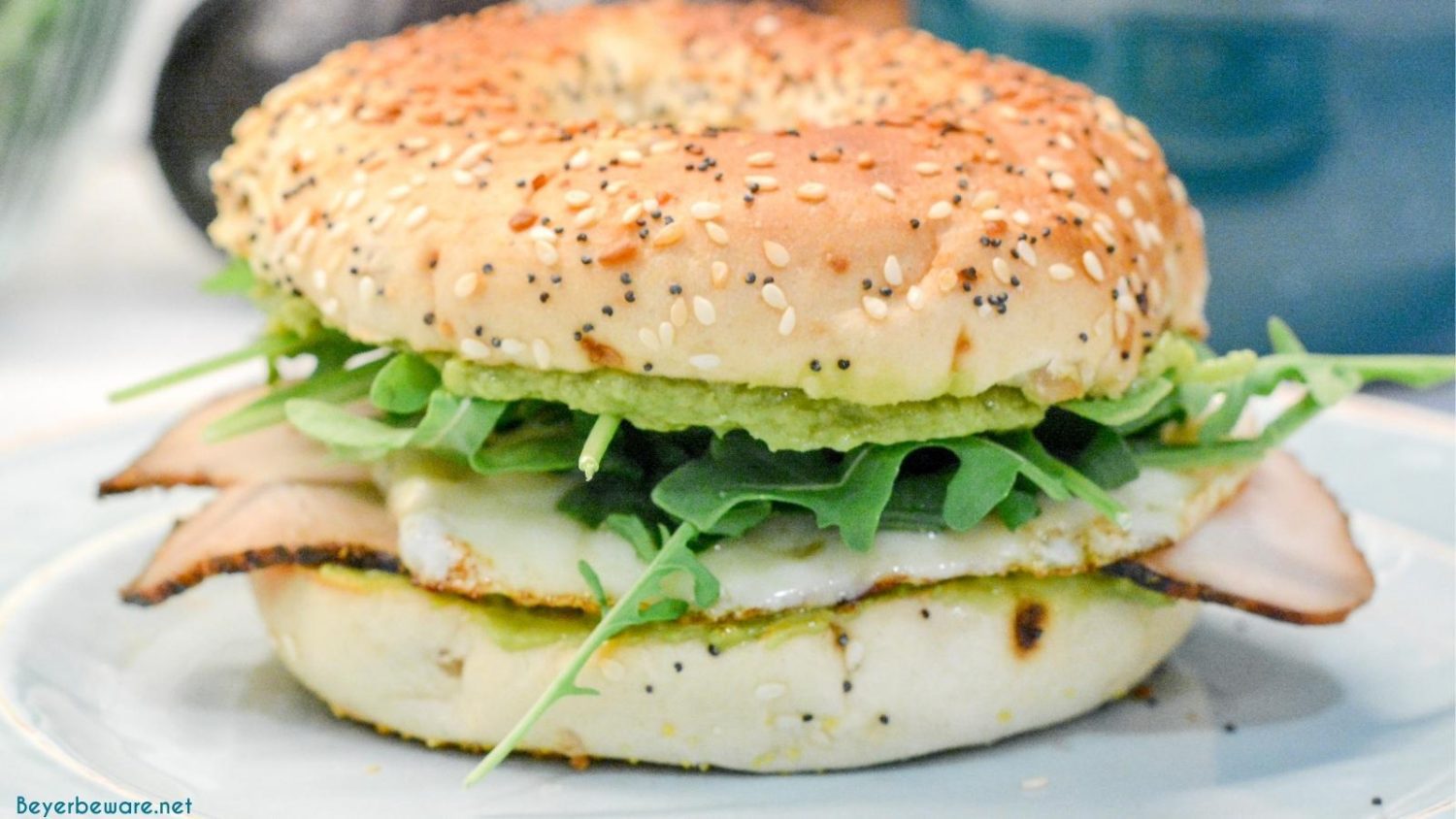 This everything bagel egg sandwich is filled with avocado, turkey, egg, cheese, and topped off with arugula. 