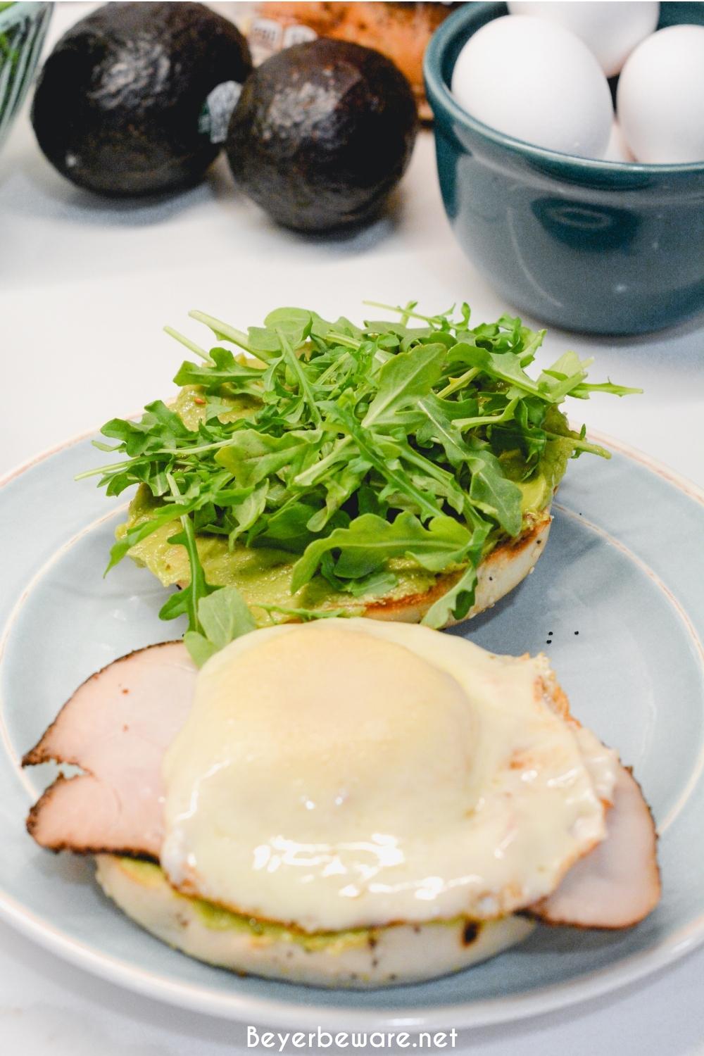 This everything bagel egg sandwich is filled with avocado, turkey, egg, cheese, and topped off with arugula. 