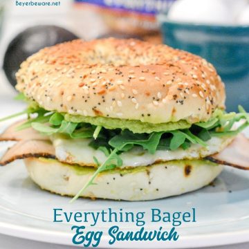 This everything bagel egg sandwich is filled with avocado, turkey, egg, cheese, and topped off with arugula.