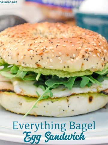 This everything bagel egg sandwich is filled with avocado, turkey, egg, cheese, and topped off with arugula.