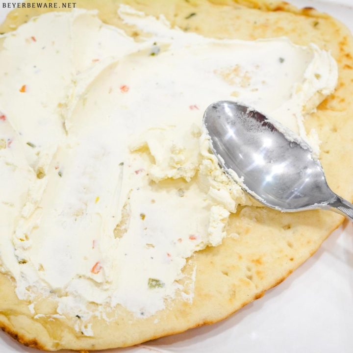 Spread the seasoned cream cheese on the flat side of the naan bread.