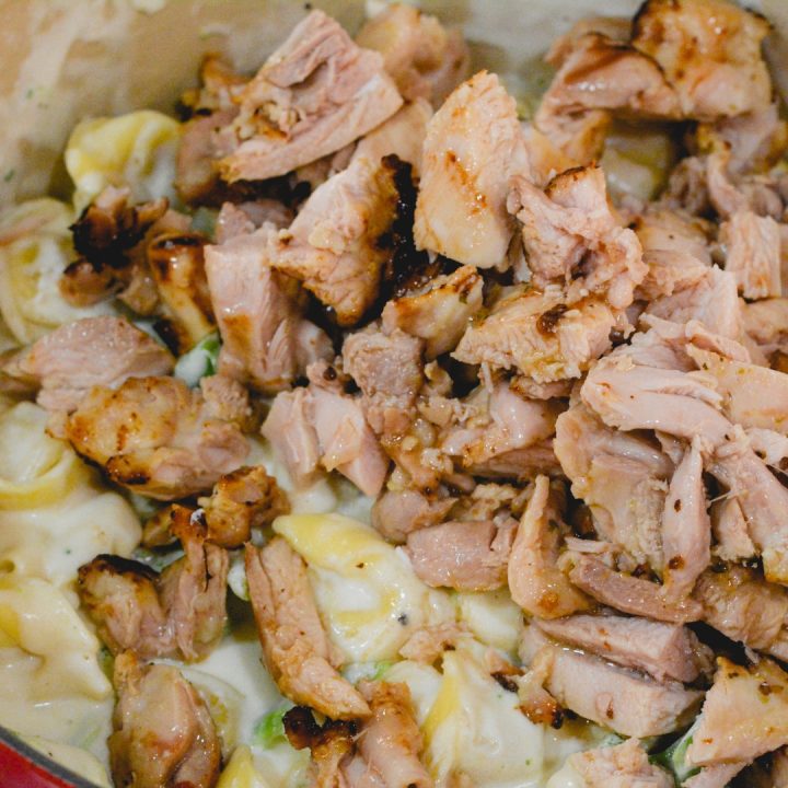 Slice cooked chicken and add to the alfredo sauce, tortellini and chicken. Stir the chicken into the alfredo sauce. Keep a very low heat on to melt the cheese.