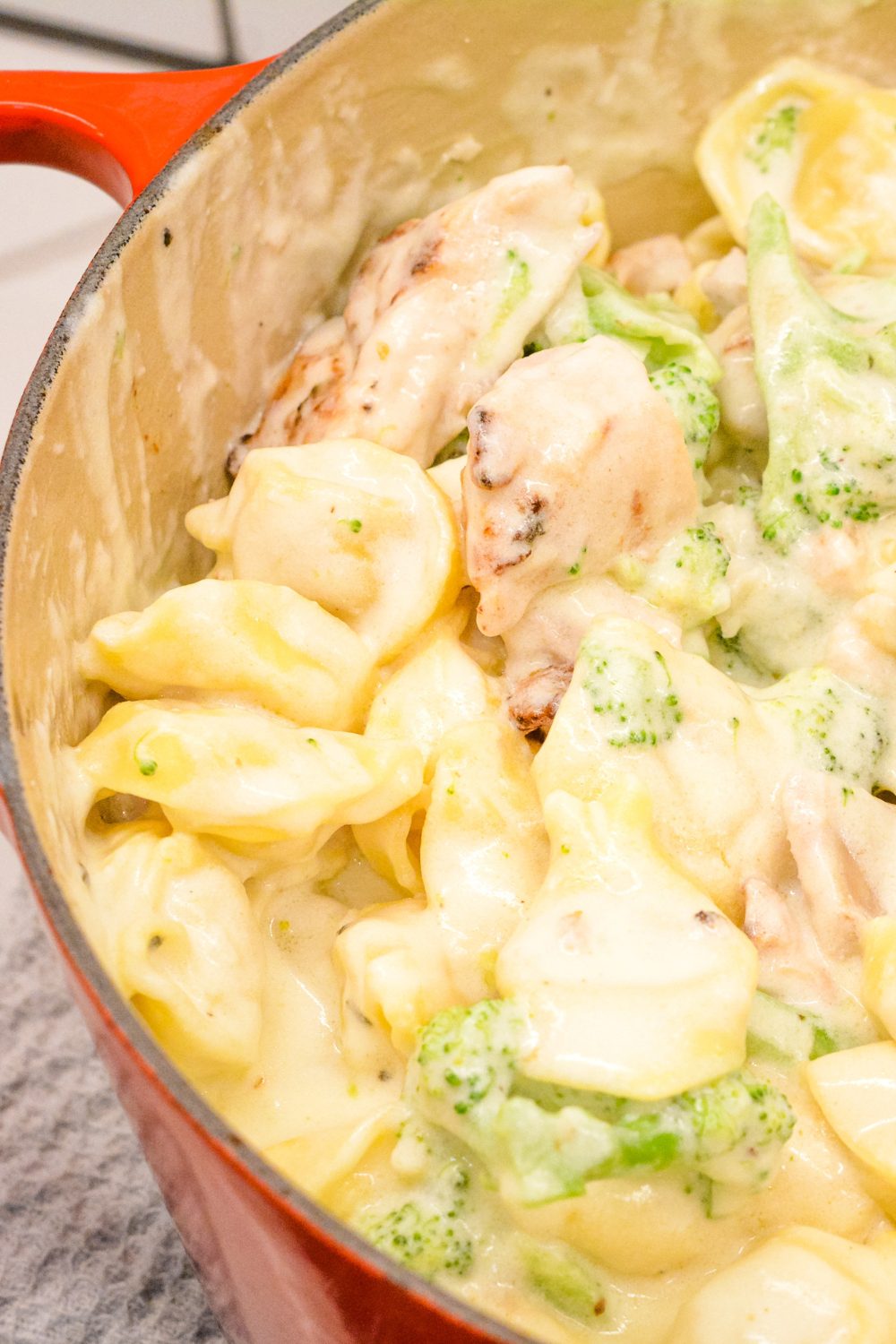 Slice cooked chicken and add to the alfredo sauce, tortellini and chicken. Stir the chicken into the alfredo sauce. Keep a very low heat on to melt the cheese. 