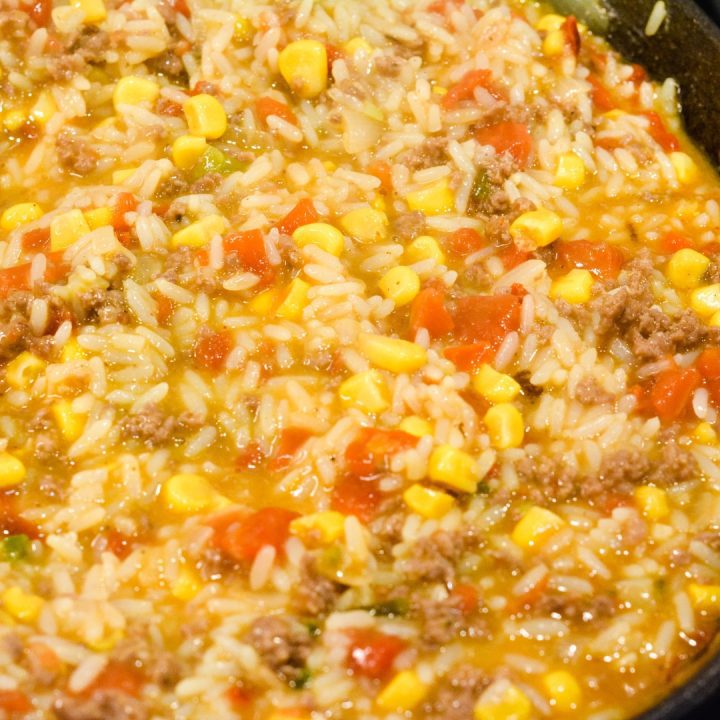 When the rice is soft, on cover the rice and ground beef skillet. Pour the queso cheese sauce over the top of the rice and beef. 